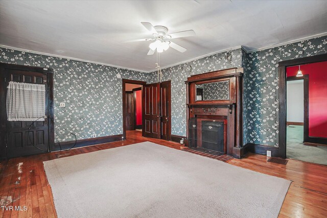 454 Cedar St, Bluff City, TN 37618 - unfurnished living room with wood-type flooring, ceiling fan, ornamental molding, wallpapered walls, and a fireplace with flush hearth