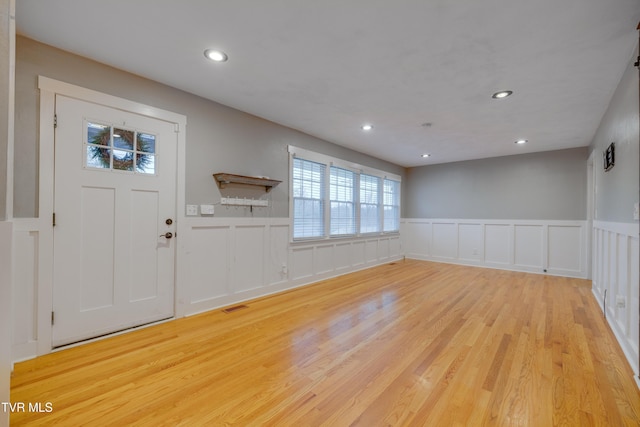 entrance foyer featuring a decorative wall, wood finished floors, a wainscoted wall, and recessed lighting
