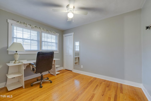 home office featuring light wood finished floors, a ceiling fan, and baseboards