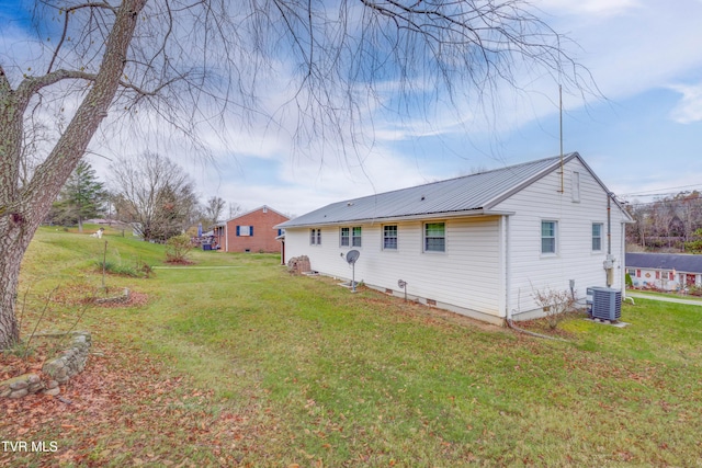 rear view of house featuring central AC, a yard, and metal roof