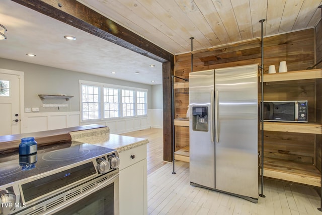 kitchen featuring stainless steel appliances, light wood-style floors, a wainscoted wall, recessed lighting, and plenty of natural light