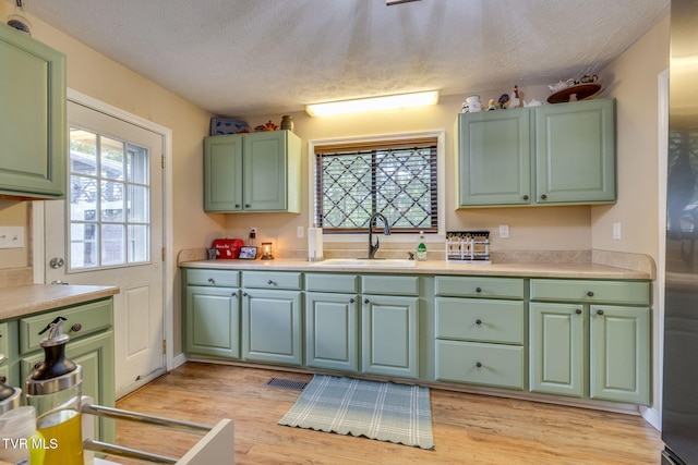 373 Mckeehan Ridge Rd, Elizabethton, TN 37643 - kitchen with a sink, a textured ceiling, green cabinets, light wood-style flooring, and light countertops