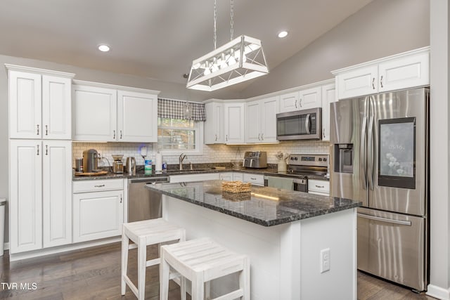 kitchen featuring stainless steel appliances, a sink, white cabinets, backsplash, and vaulted ceiling