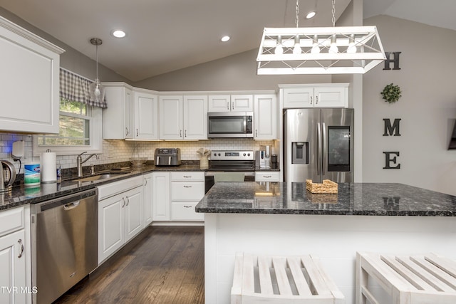 kitchen with stainless steel appliances, vaulted ceiling, a sink, tasteful backsplash, and white cabinetry