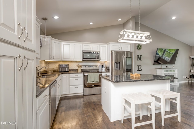 kitchen featuring stainless steel appliances, a sink, white cabinetry, a breakfast bar, and tasteful backsplash