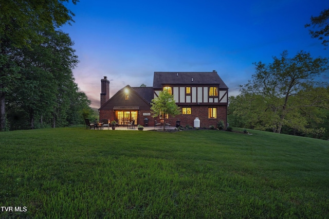 150 NW New Melrose St, Coeburn, VA 24230 - back of house at dusk with a chimney, a lawn, a patio area, and brick siding