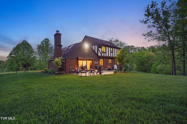 150 NW New Melrose St, Coeburn, VA 24230 - back of house at dusk with a patio, a yard, a chimney, and brick siding