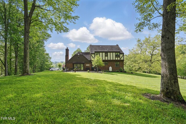 150 NW New Melrose St, Coeburn, VA 24230 - back of property featuring brick siding, a yard, a patio area, and a chimney