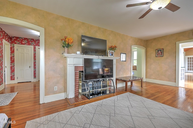 15497 Porterfield Hwy, Abingdon, VA 24210 - living room with arched walkways, wood finished floors, a fireplace, a ceiling fan, and baseboards