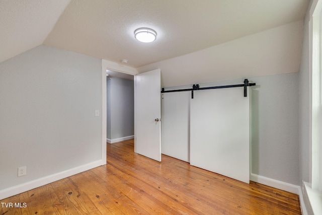 3224 Clover St, Kingsport, TN 37664 - unfurnished bedroom with lofted ceiling, a barn door, light wood-type flooring, a closet, and baseboards