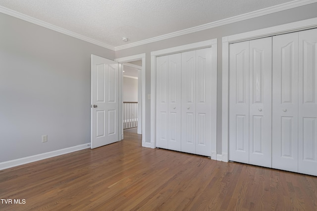 7540 Erwin Hwy, Chuckey, TN 37641 - unfurnished bedroom with two closets, wood finished floors, baseboards, a textured ceiling, and crown molding