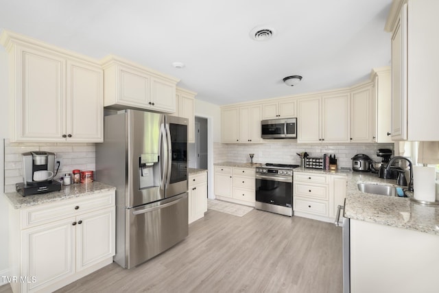 405 Castaway Dr, Kingsport, TN 37663 - kitchen featuring appliances with stainless steel finishes, cream cabinetry, a sink, backsplash, and light wood finished floors