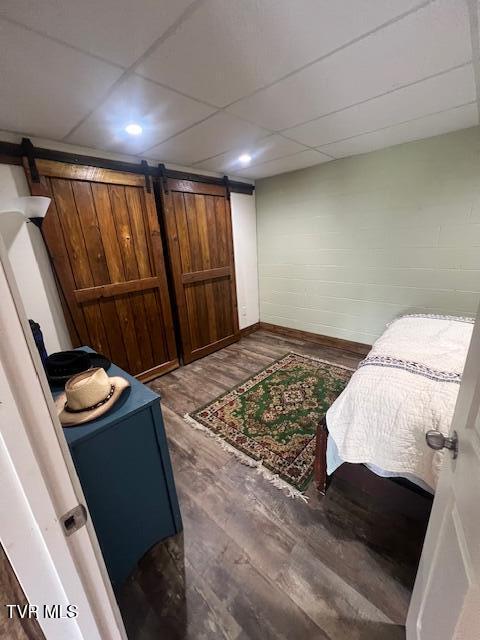 365 Guthrie Greene Rd, Bulls Gap, TN 37711 - bedroom with a barn door, dark wood-type flooring, baseboards, a drop ceiling, and recessed lighting