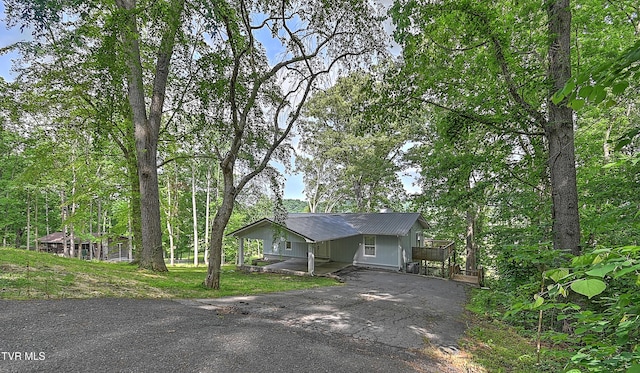 view of front of house with asphalt driveway, a wooden deck, and metal roof