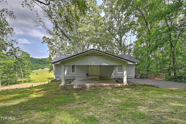 view of front of home with metal roof, asphalt driveway, a front lawn, a patio, and a carport