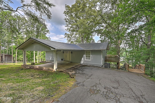 view of front of property featuring metal roof, asphalt driveway, a deck, central AC, and a carport