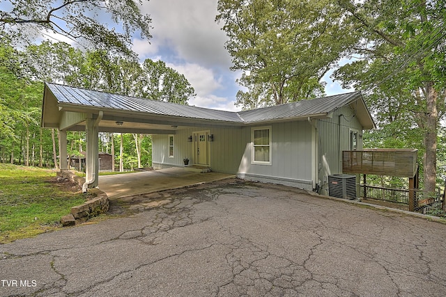view of front of house with a carport, driveway, cooling unit, and metal roof