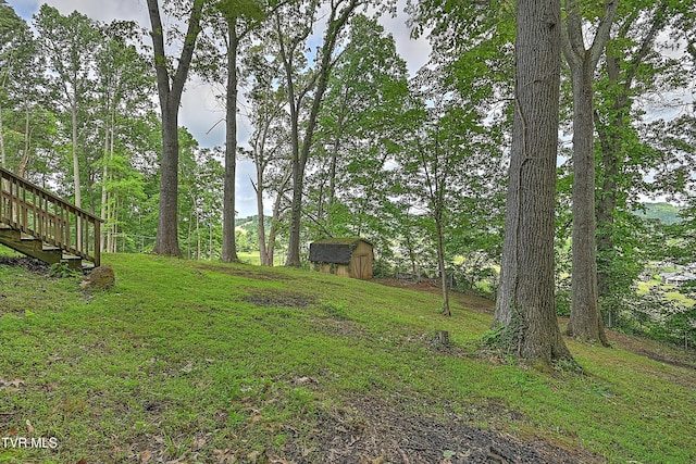 view of green lawn featuring a storage shed, an outdoor structure, and stairway