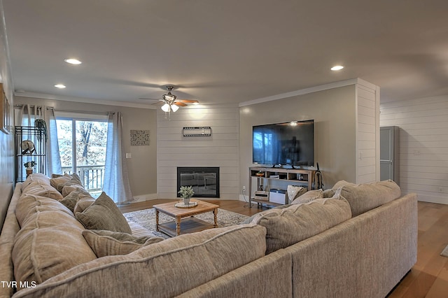 living room with ornamental molding, a ceiling fan, wood finished floors, a large fireplace, and recessed lighting