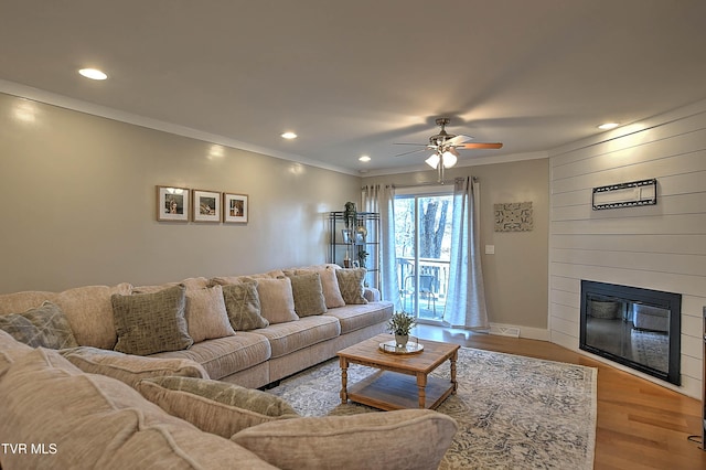 living area with wood finished floors, ceiling fan, a fireplace, crown molding, and recessed lighting