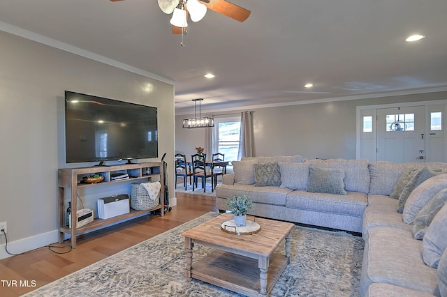 living area featuring wood finished floors, crown molding, ceiling fan, recessed lighting, and baseboards