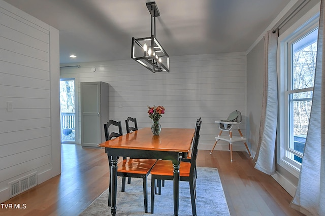 dining space featuring wood finished floors, wooden walls, a chandelier, and recessed lighting