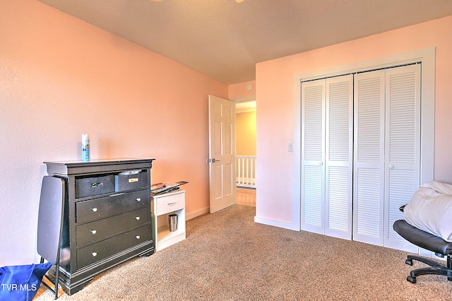 carpeted bedroom featuring a closet and baseboards