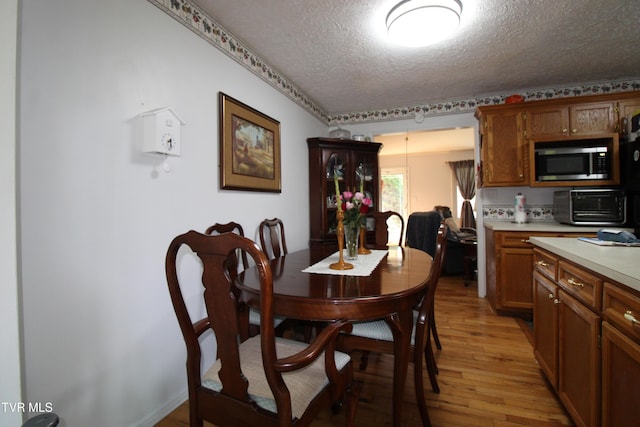16319 Mary St, Abingdon, VA 24210 - kitchen with a textured ceiling, stainless steel microwave, light countertops, light wood-style flooring, and brown cabinetry