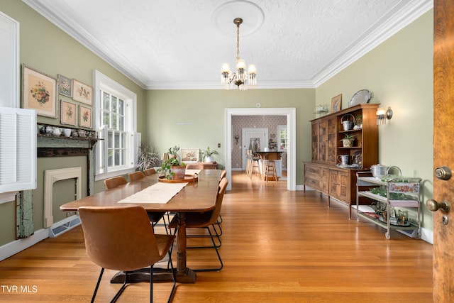 2107 Bartlett St, Johnson City, TN 37601 - dining space featuring a textured ceiling, a chandelier, crown molding, light wood-style floors, and a fireplace with flush hearth