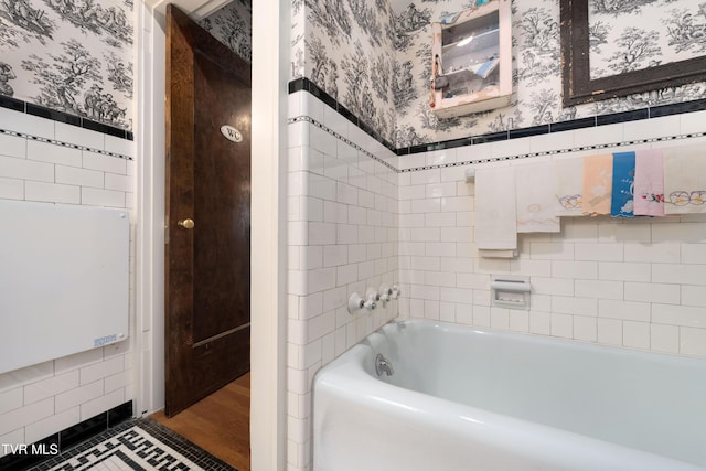 2107 Bartlett St, Johnson City, TN 37601 - bathroom featuring wallpapered walls, tile walls, a bathtub, and wainscoting