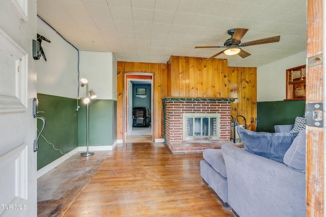 7175 Reedy Creek Rd, Bristol, VA 24202 - living room featuring ceiling fan, a brick fireplace, wood finished floors, wooden walls, and baseboards