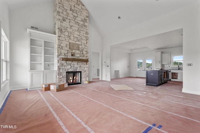 unfurnished living room featuring high vaulted ceiling, baseboards, a fireplace, and a sink