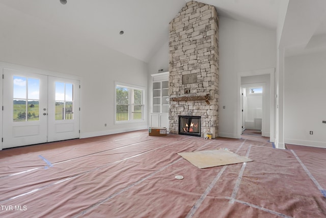 unfurnished living room featuring high vaulted ceiling, french doors, a fireplace, and baseboards