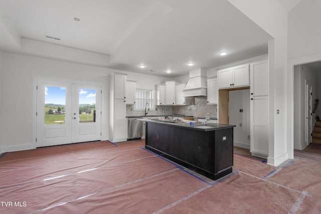 kitchen with custom exhaust hood, stainless steel dishwasher, white cabinets, a kitchen island, and a sink