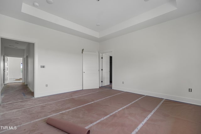 unfurnished bedroom featuring a raised ceiling and baseboards
