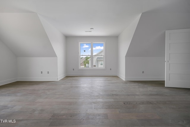 additional living space featuring wood finished floors, baseboards, and lofted ceiling