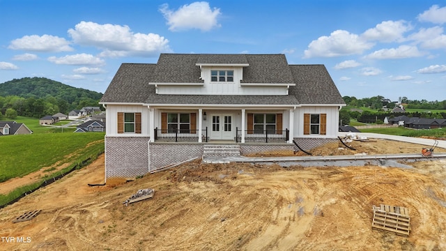 modern inspired farmhouse featuring roof with shingles, french doors, a front yard, and a porch