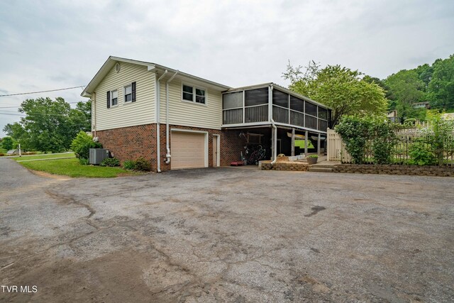 137 Highland Rd, Jonesborough, TN 37659 - view of side of home with brick siding, central AC, asphalt driveway, a sunroom, and an attached garage