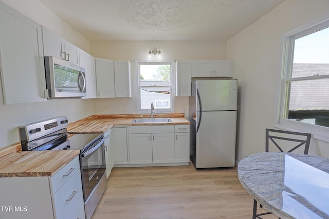 329 Clinch St, Kingsport, TN 37660 - kitchen featuring appliances with stainless steel finishes, butcher block countertops, a sink, light wood-type flooring, and a textured ceiling