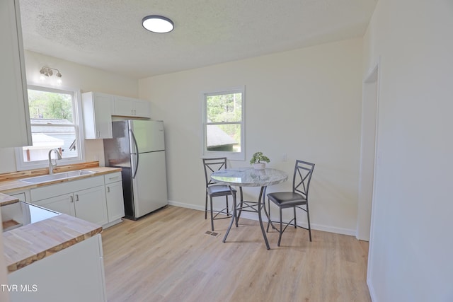 329 Clinch St, Kingsport, TN 37660 - kitchen with a sink, freestanding refrigerator, light wood-style flooring, a textured ceiling, and white cabinets