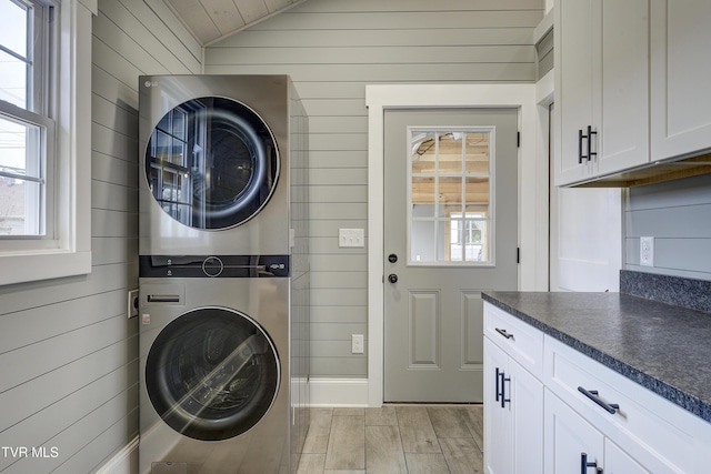 403 Catawba St, Erwin, TN 37650 - laundry area featuring estacked washer and dryer, cabinet space, wood walls, and light wood-style flooring