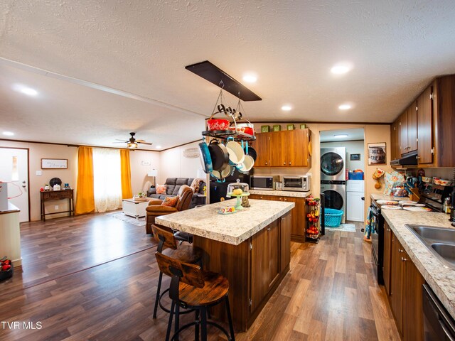 1029 Red Bud Ln, Rogersville, TN 37857 - kitchen featuring stainless steel microwave, stacked washing machine and dryer, under cabinet range hood, light countertops, and black / electric stove