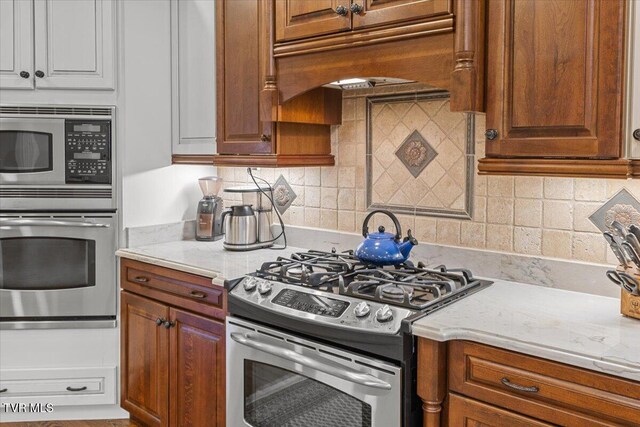 114 Highland Gate Dr, Johnson City, TN 37615 - kitchen featuring appliances with stainless steel finishes, premium range hood, decorative backsplash, and brown cabinets
