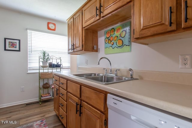 14227 Wellbridge Dr, Meadowview, VA 24361 - kitchen featuring dishwasher, a sink, light countertops, light wood finished floors, and brown cabinetry