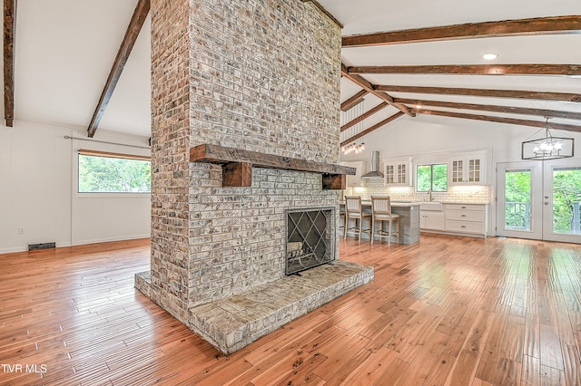 28 Kingsbridge St, Bristol, TN 37620 - unfurnished living room featuring light wood-style flooring, beamed ceiling, a fireplace, a sink, and a chandelier