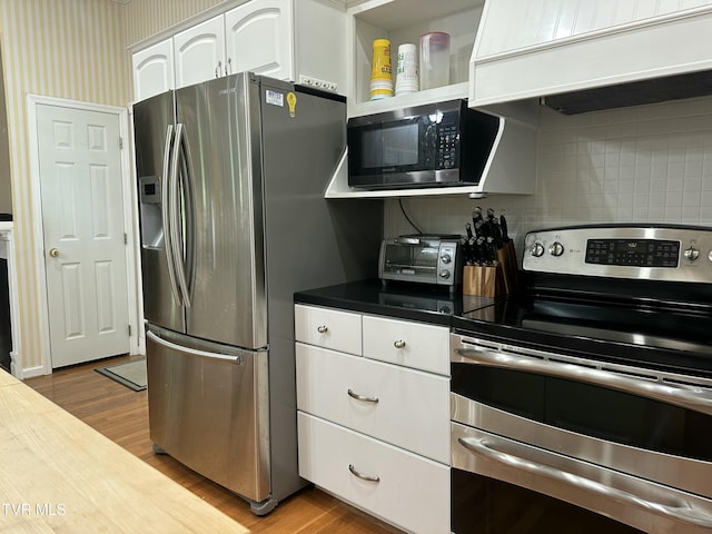 390 Springdale Dr, Bristol, TN 37620 - kitchen with appliances with stainless steel finishes, custom exhaust hood, white cabinets, light wood-style floors, and tasteful backsplash