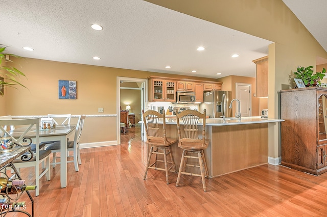 105 Morse Dr, Bristol, TN 37620 - kitchen featuring appliances with stainless steel finishes, a peninsula, light wood-style floors, a breakfast bar, and glass insert cabinets