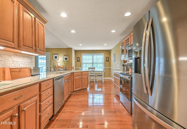 105 Morse Dr, Bristol, TN 37620 - kitchen featuring stainless steel appliances, a textured ceiling, a peninsula, light wood-style floors, and backsplash