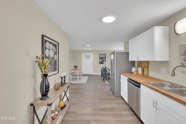 1241 Virginia Ave, Bristol, TN 37620 - kitchen with stainless steel appliances, a sink, white cabinets, light wood-style floors, and baseboards