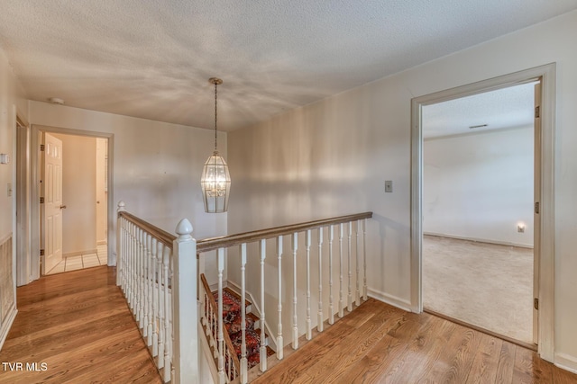 3510 Bondwood Cir, Johnson City, TN 37604 - hallway featuring an upstairs landing, wood finished floors, a chandelier, a textured ceiling, and baseboards